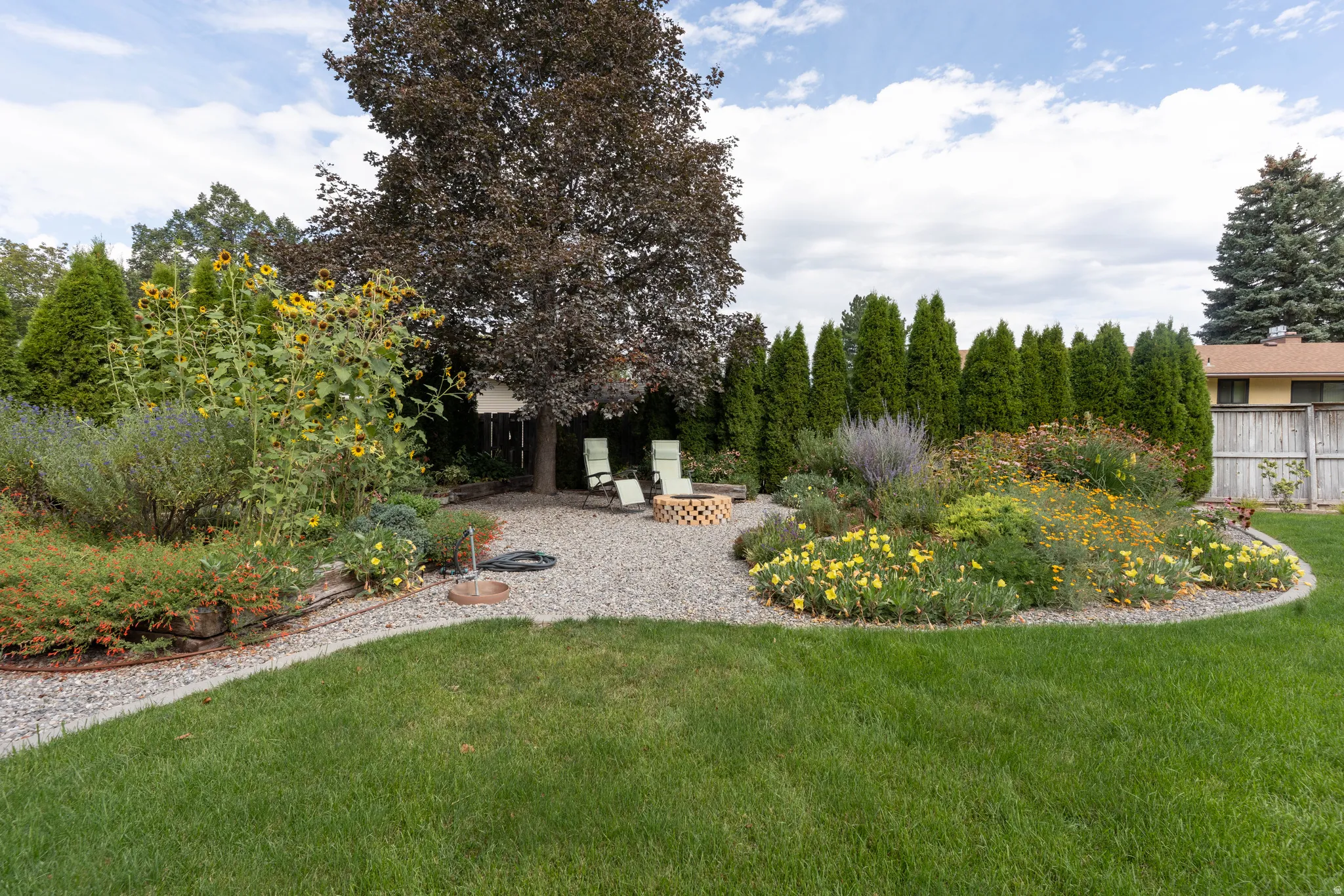 Manicured lawn with a gravel patio featuring a fire pit