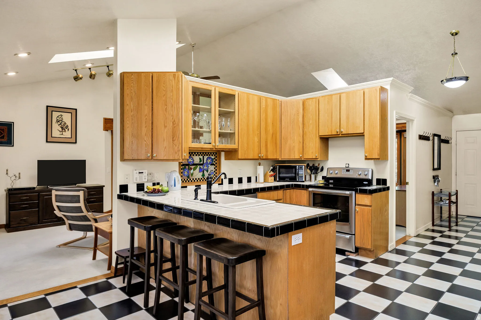 Kitchen with wood cabinetry, stainless steel appliances, breakfast bar, and checkerboard floor tiling