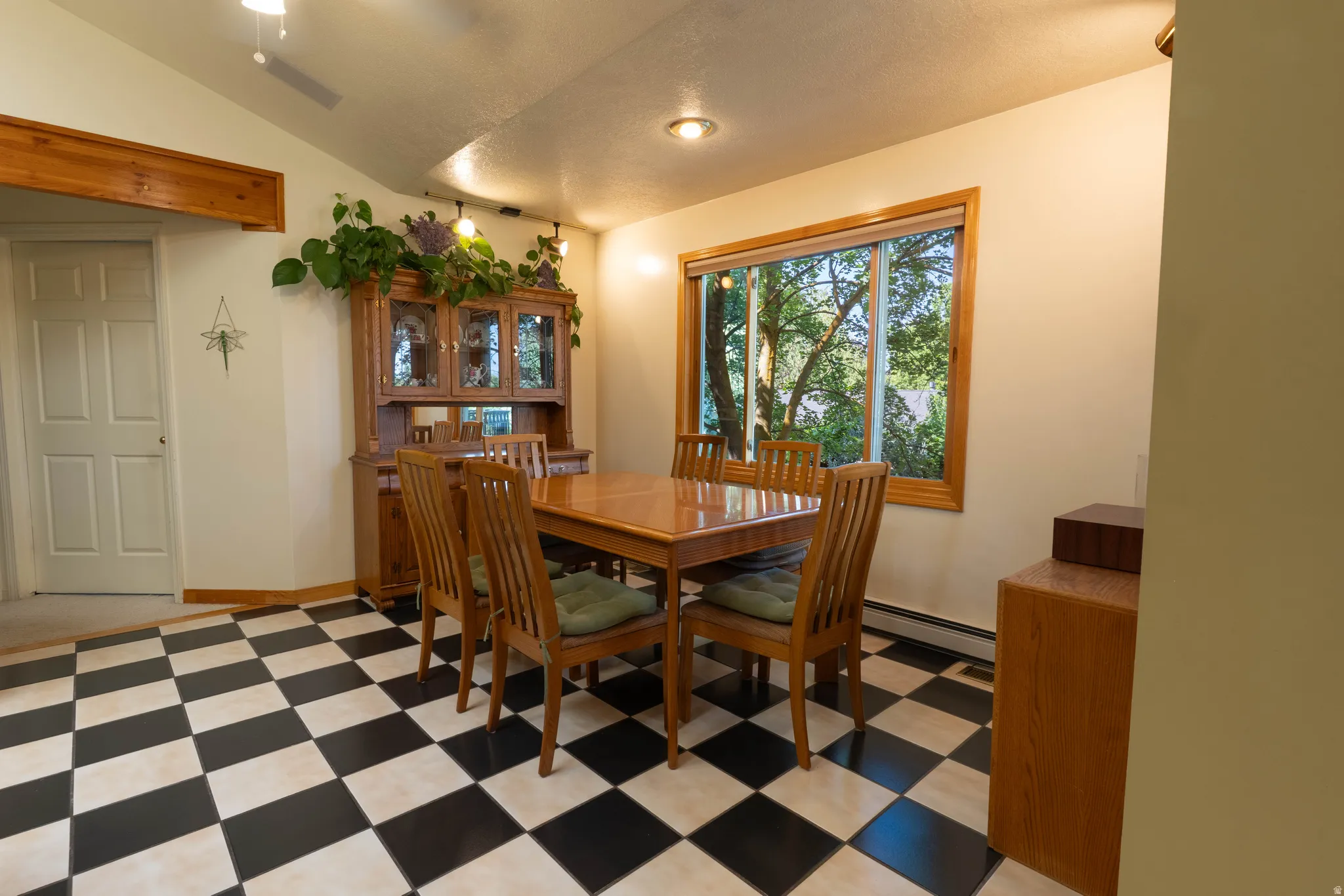 Checkered tile flooring, large wood-framed window, recessed lighting, and a vaulted ceiling