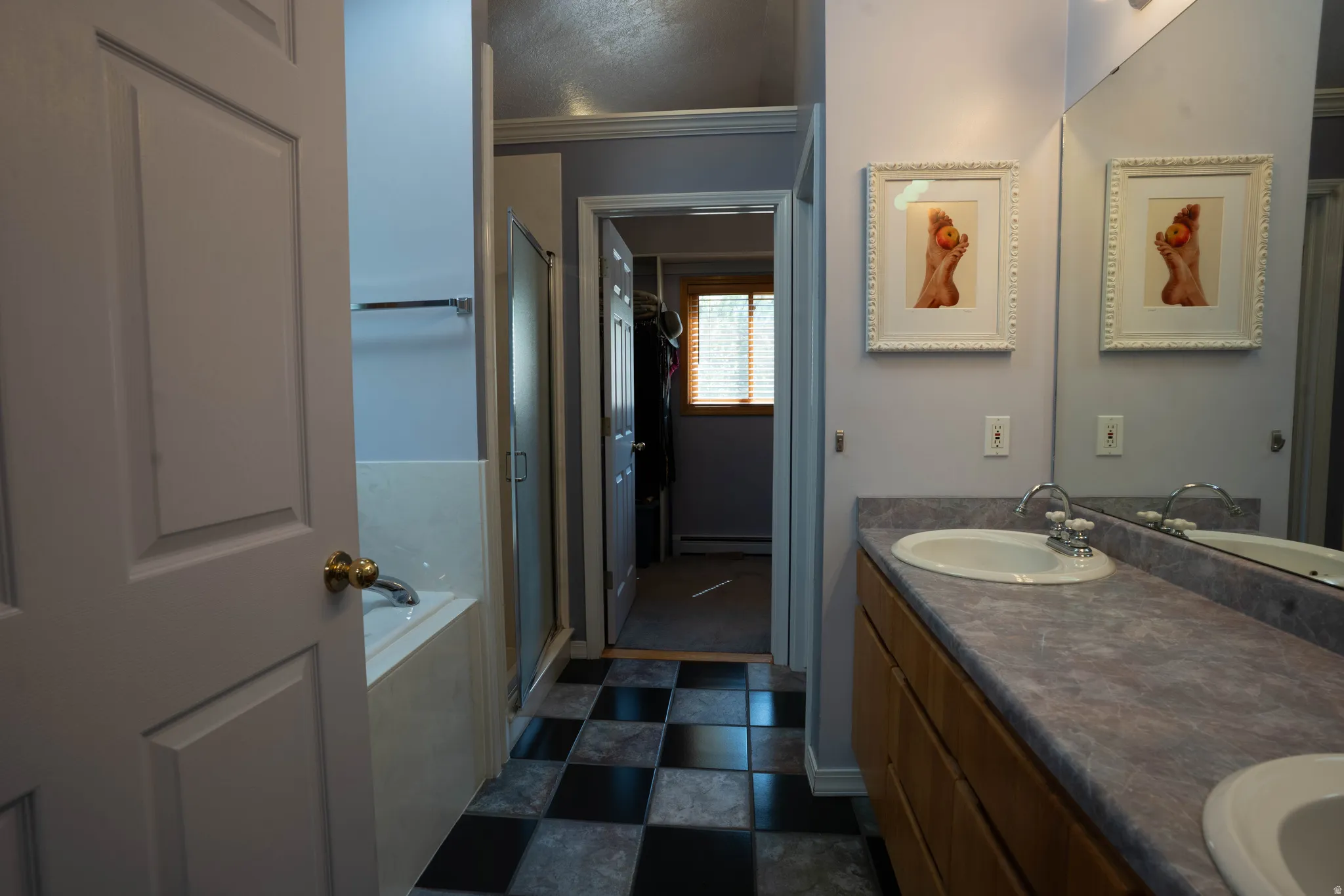Dual sink vanity with laminate countertop, checkered tile flooring, and a built-in tub with shower enclosure