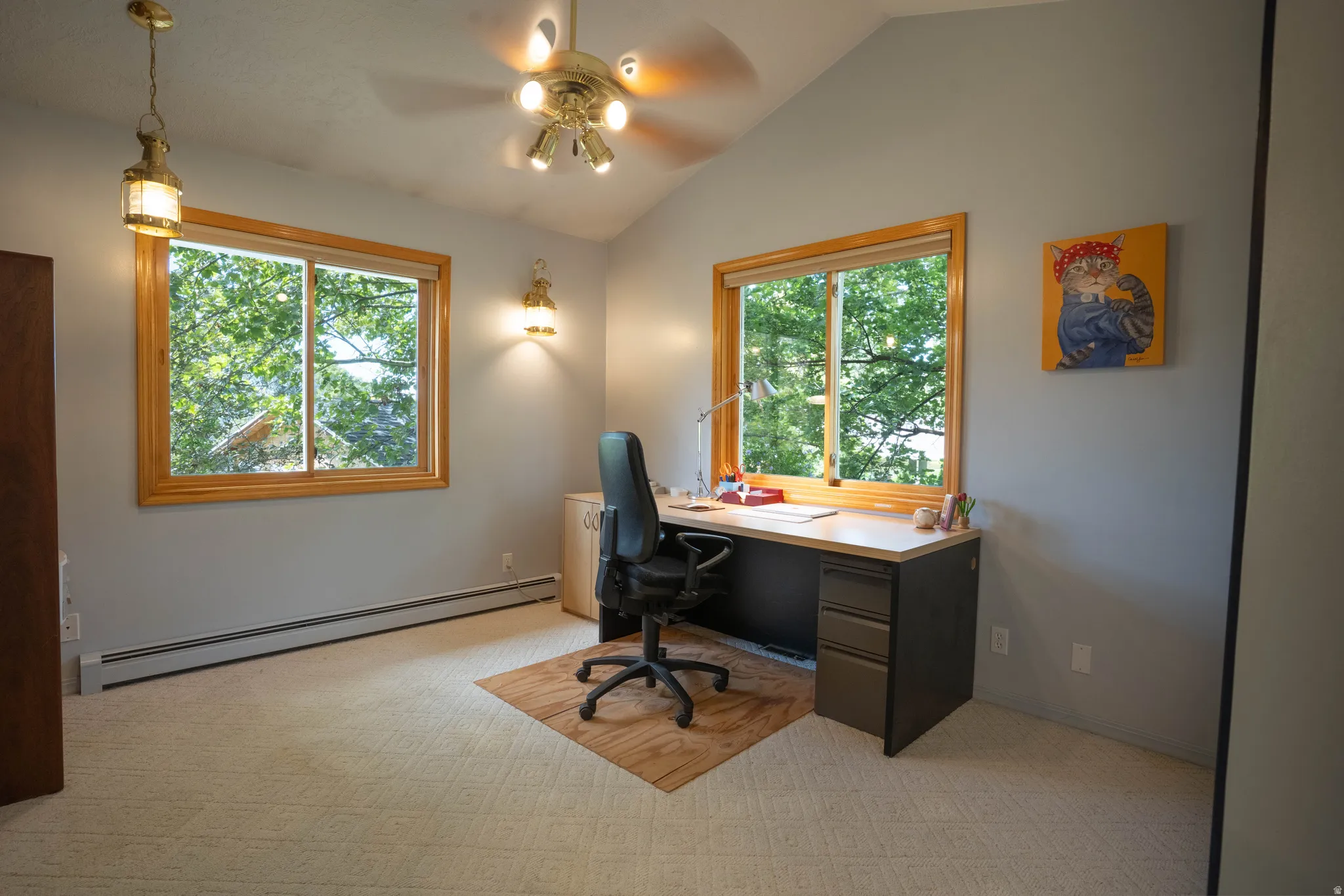 Vaulted ceiling with a brass-finish ceiling fan, wood-framed windows, wall sconce lighting, and baseboard heating