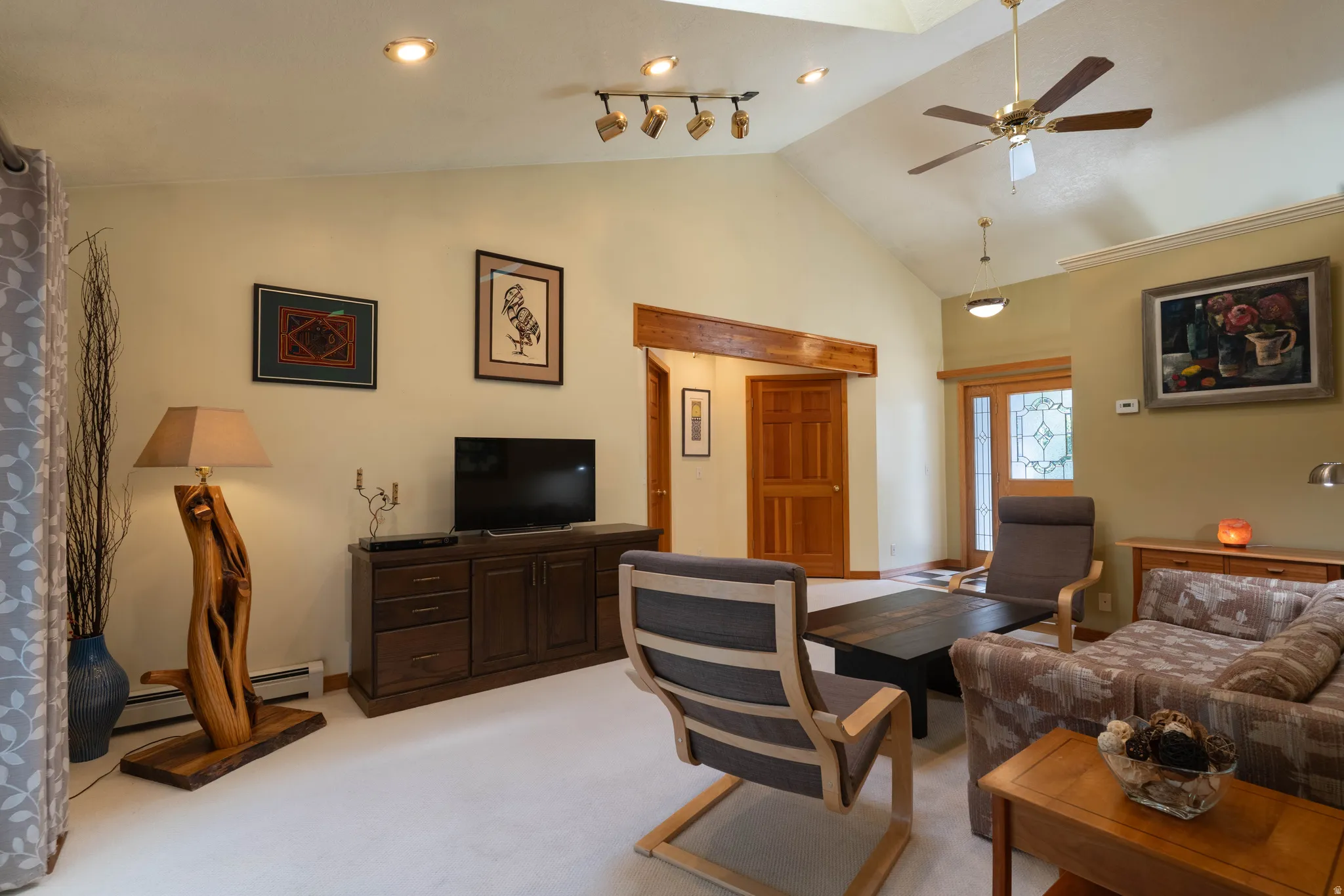 Vaulted ceiling with skylight, recessed lighting, wood trim, and a ceiling fan