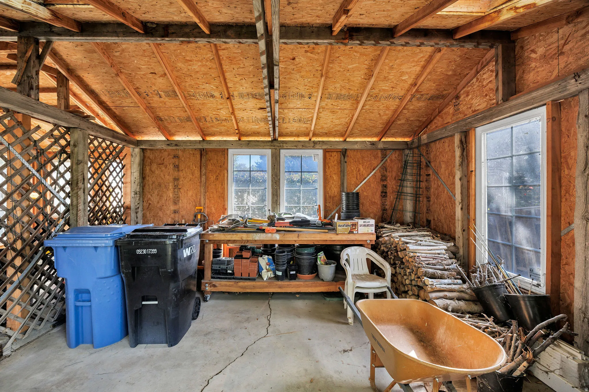 Exposed wood beam ceiling, concrete flooring, wood lattice wall, and multiple windows providing natural illumination