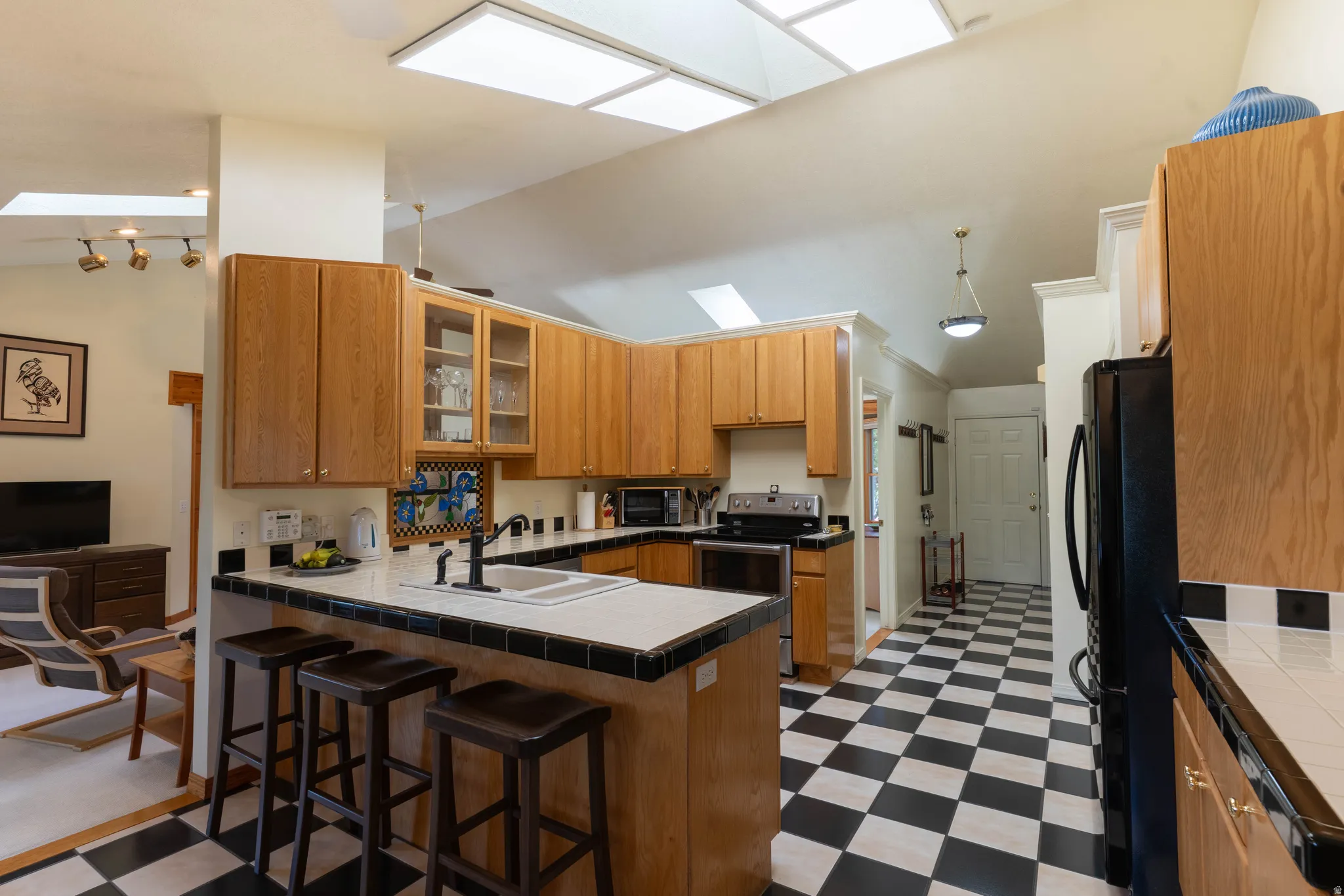 Kitchen featuring a black and white checkered floor, wood-finish cabinetry, skylights, and a breakfast bar with seating