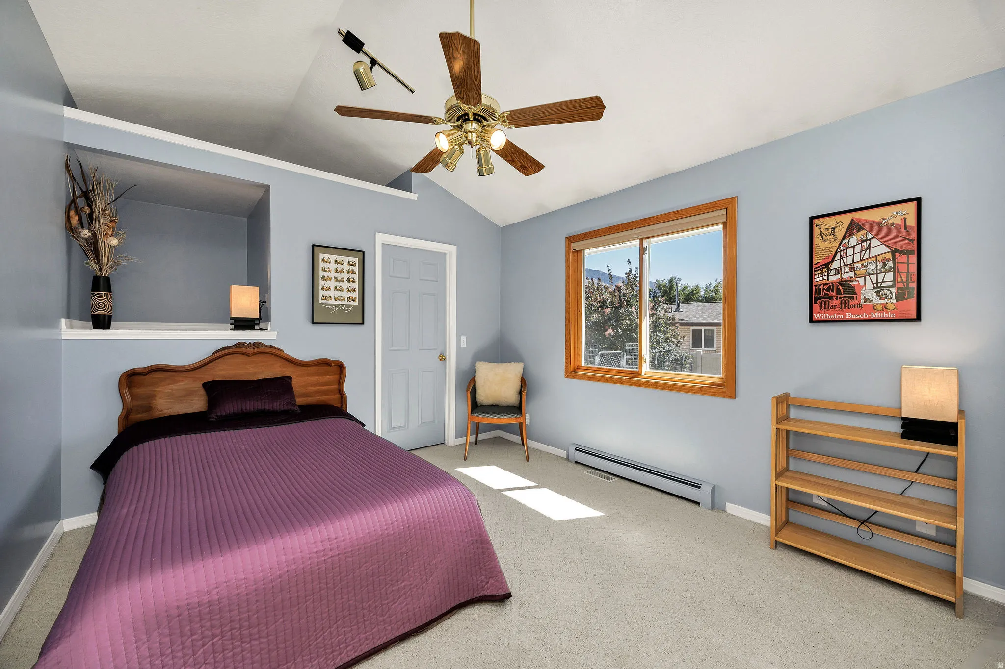 Vaulted ceiling with an attached ceiling fan, recessed wall niche, natural wood window trim, and light-toned carpet flooring