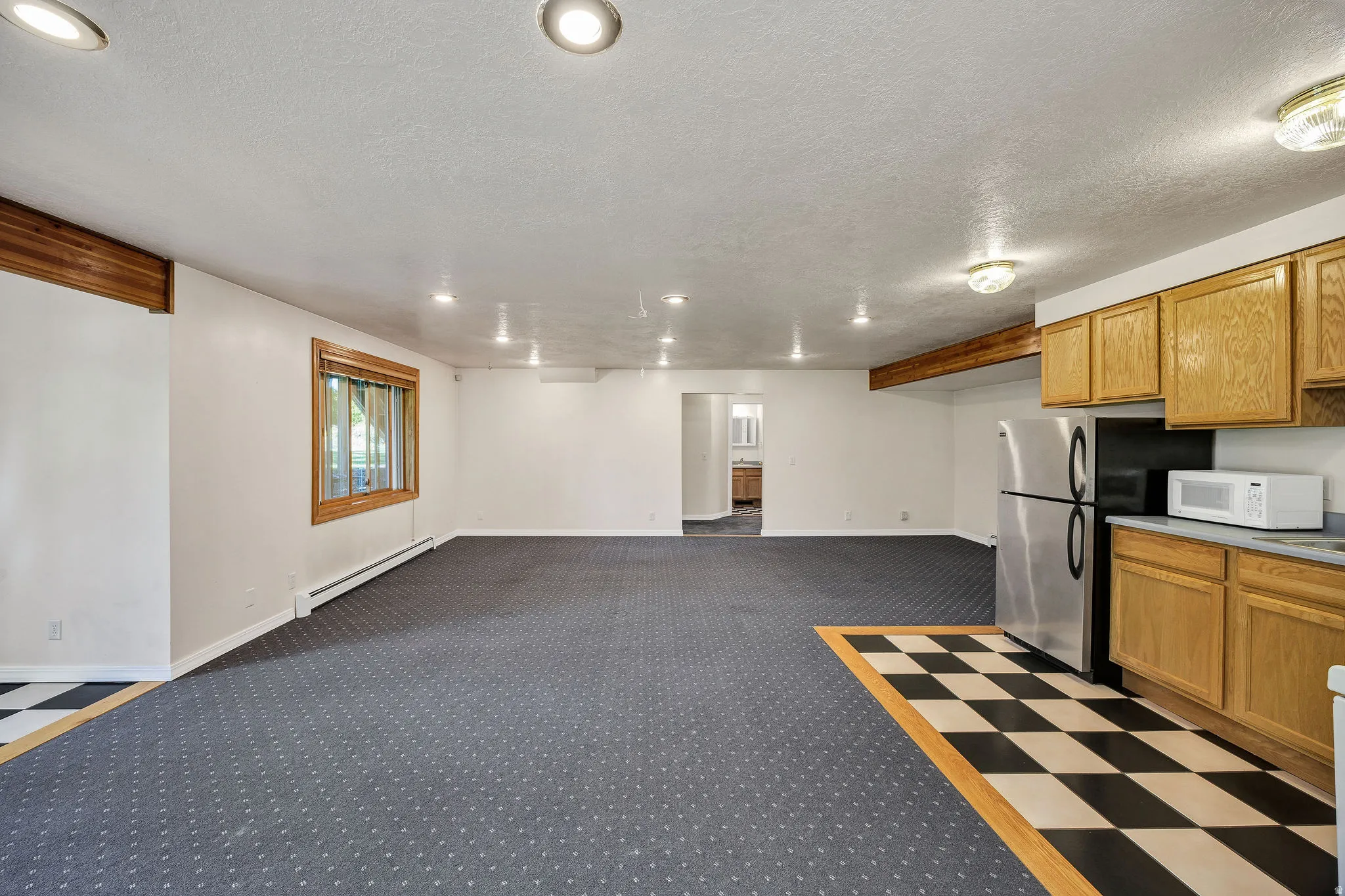 Recessed lighting, wood-finish trim, built-in cabinetry, stainless steel refrigerator, and checkerboard floor tiling