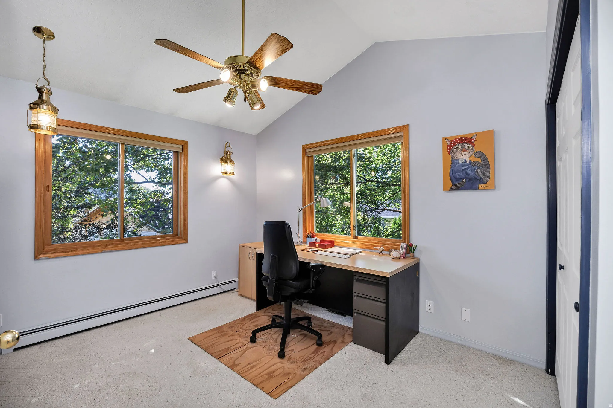 Vaulted ceiling, two windows with wood frames, ceiling fan, carpet flooring, and a built-in desk