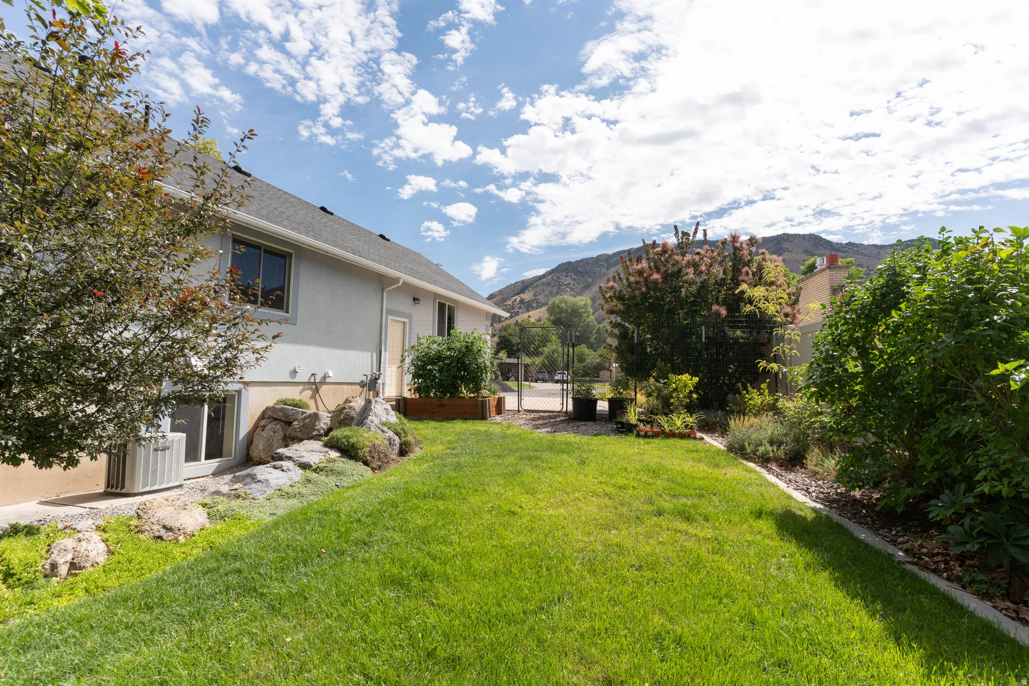 Expansive lawn with established landscaping, a raised garden bed, and a gravel border