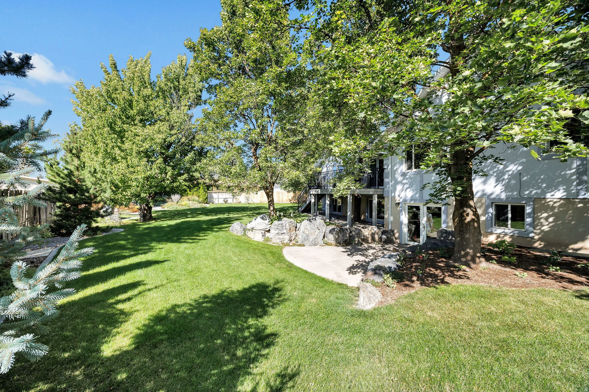 Expansive green lawn with mature trees and a concrete patio