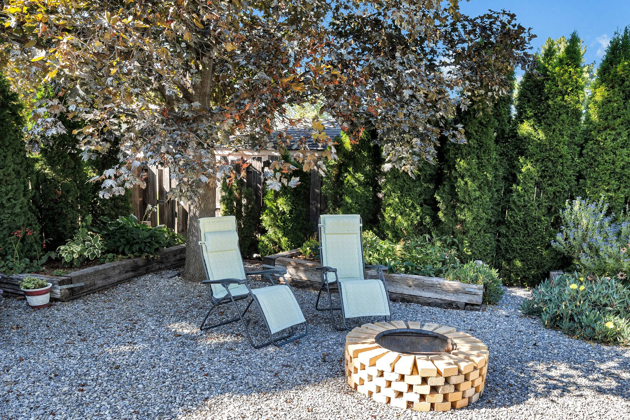 Gravel patio featuring a circular brick fire pit