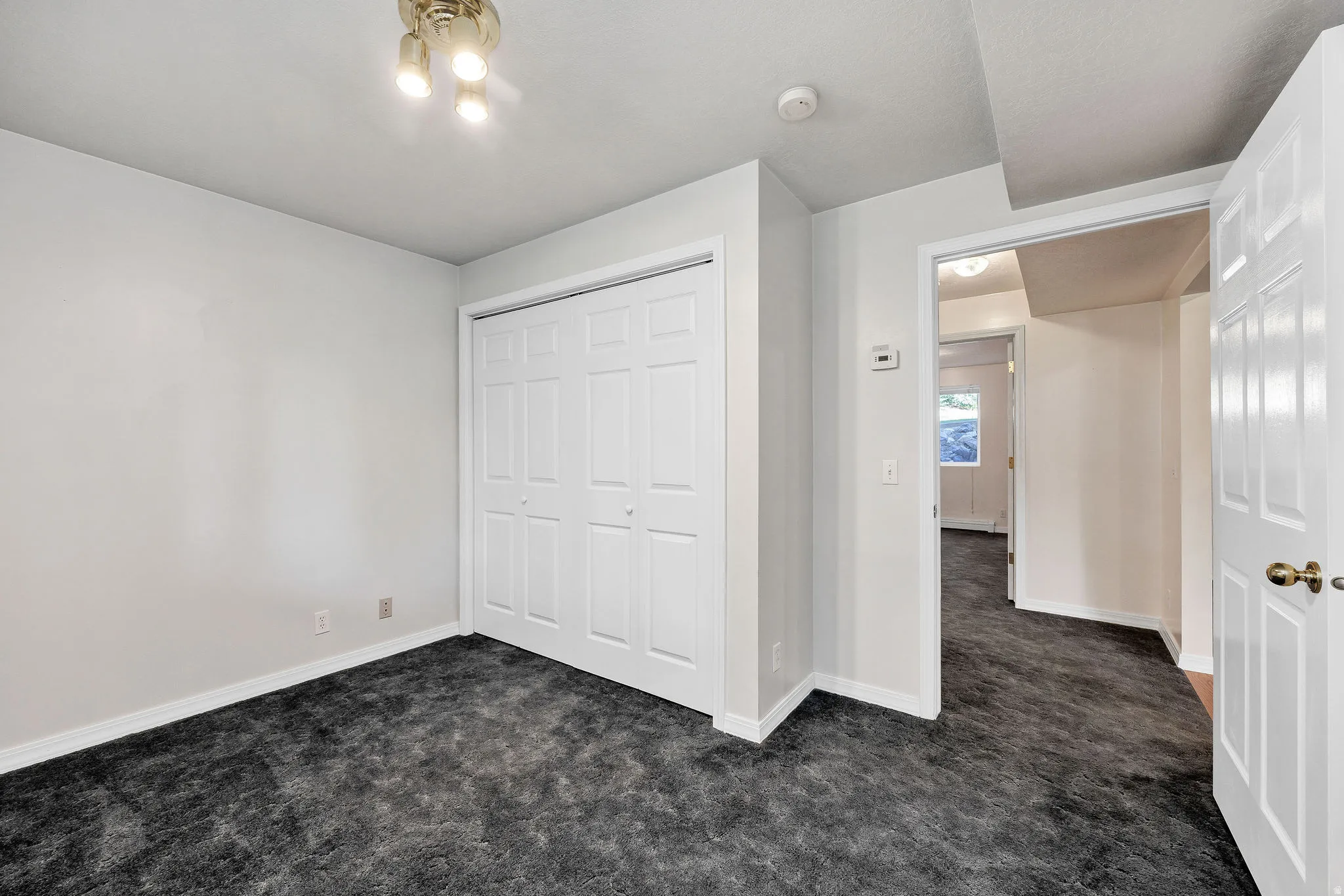 Recessed ceiling light fixture, white bi-fold closet doors, and dark-toned carpet flooring