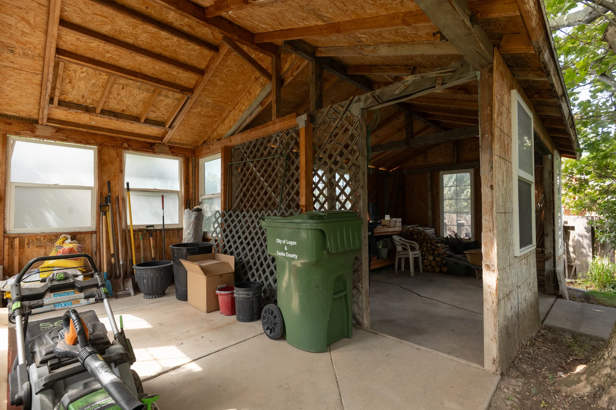 Concrete flooring, exposed wood beam ceiling, multiple windows, interior wood lattice partition