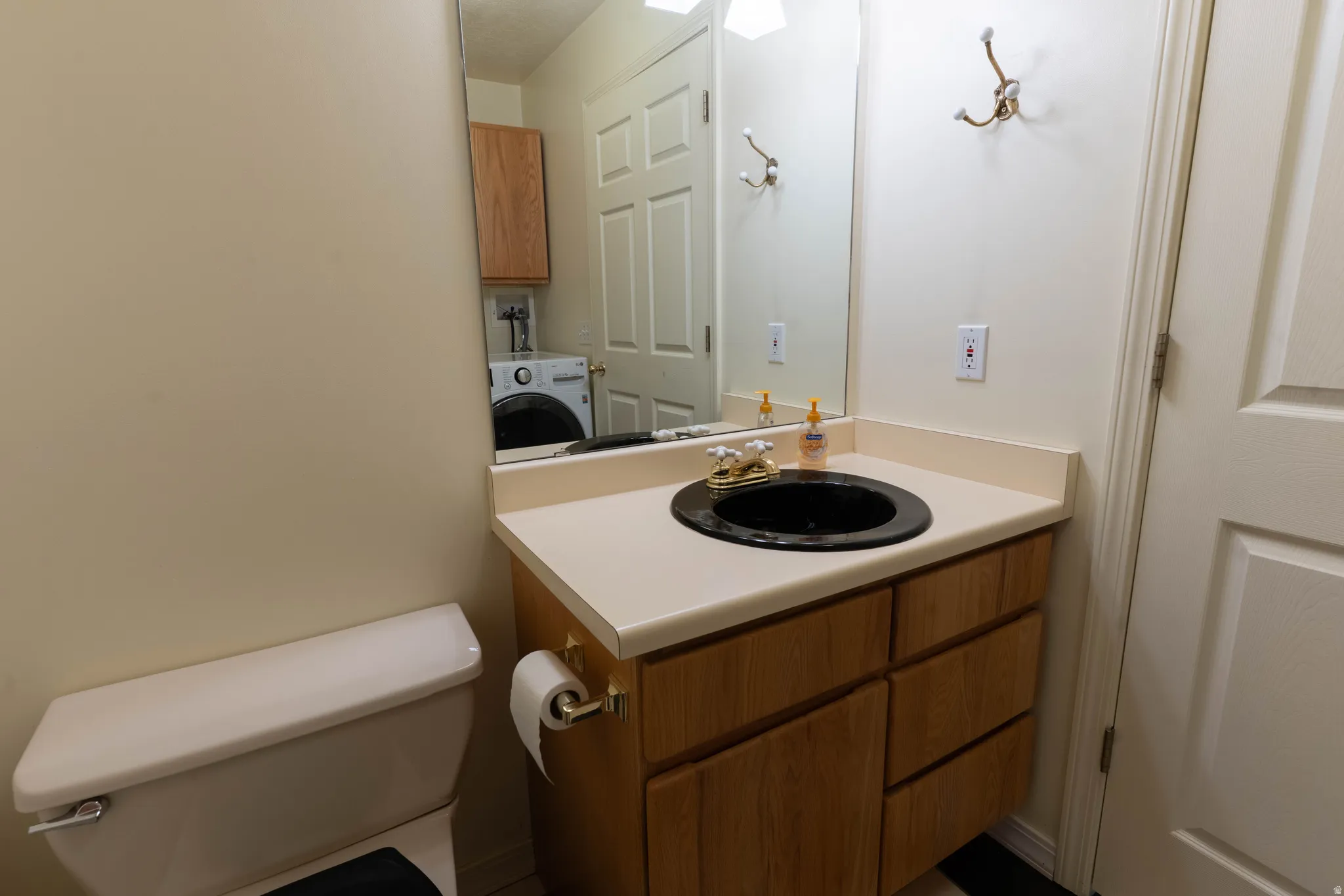 Bathroom vanity with a black basin sink, light-toned countertop, and wood-finish cabinetry
