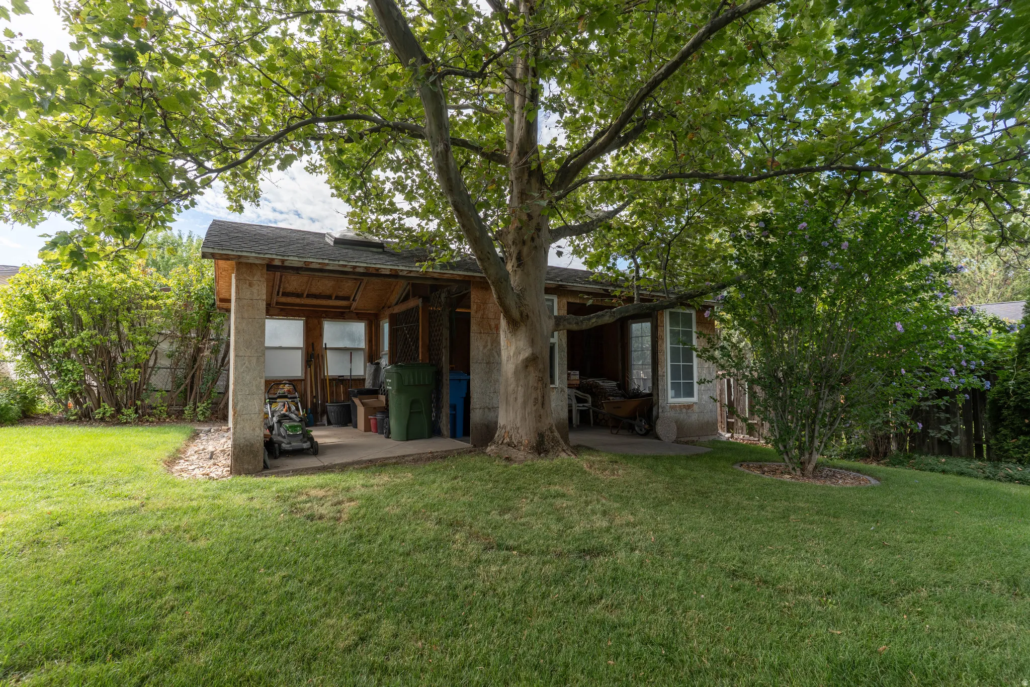 Expansive lawn featuring mature trees and a shaded concrete patio