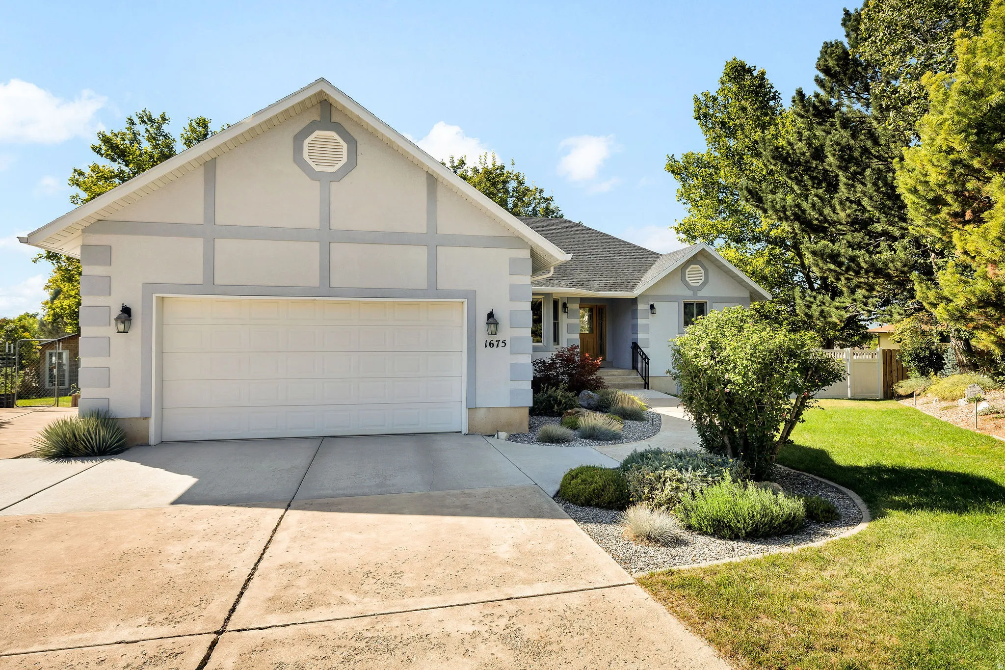 Light-toned exterior with distinct grey trim accents, attached garage with panel door, and concrete driveway