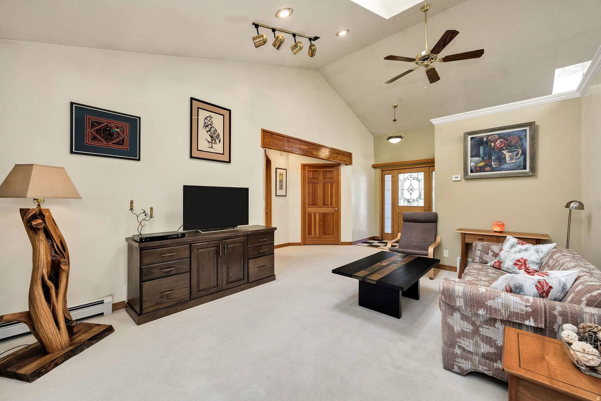 Spacious open-concept living area featuring vaulted ceilings with skylights, ceiling fan, and recessed lighting