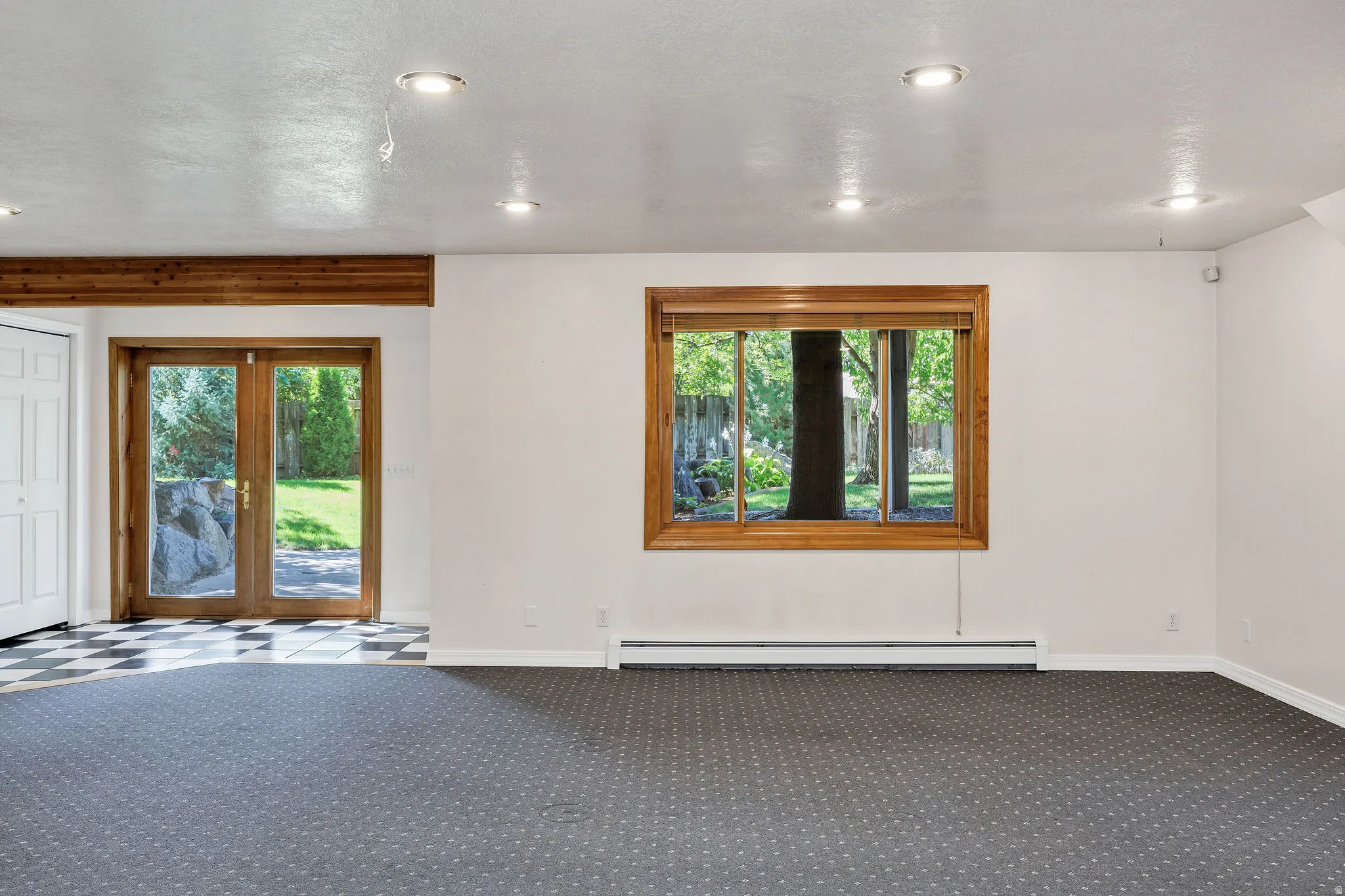 Recessed lighting throughout, a wood-framed window, and wood-framed French doors with a tile floor