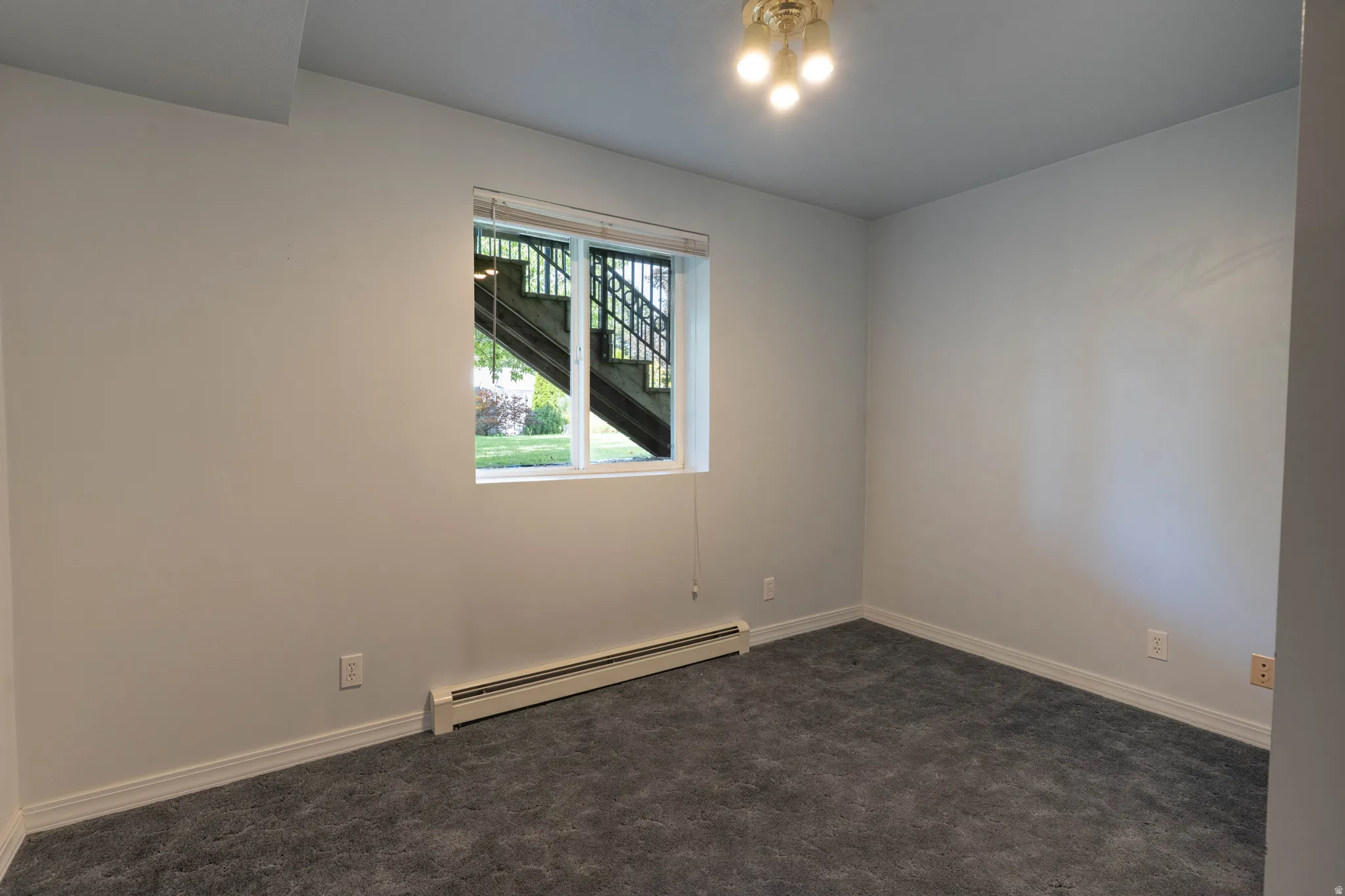 Recessed window with white trim, wall-to-wall carpeting, white painted walls, and an overhead light fixture