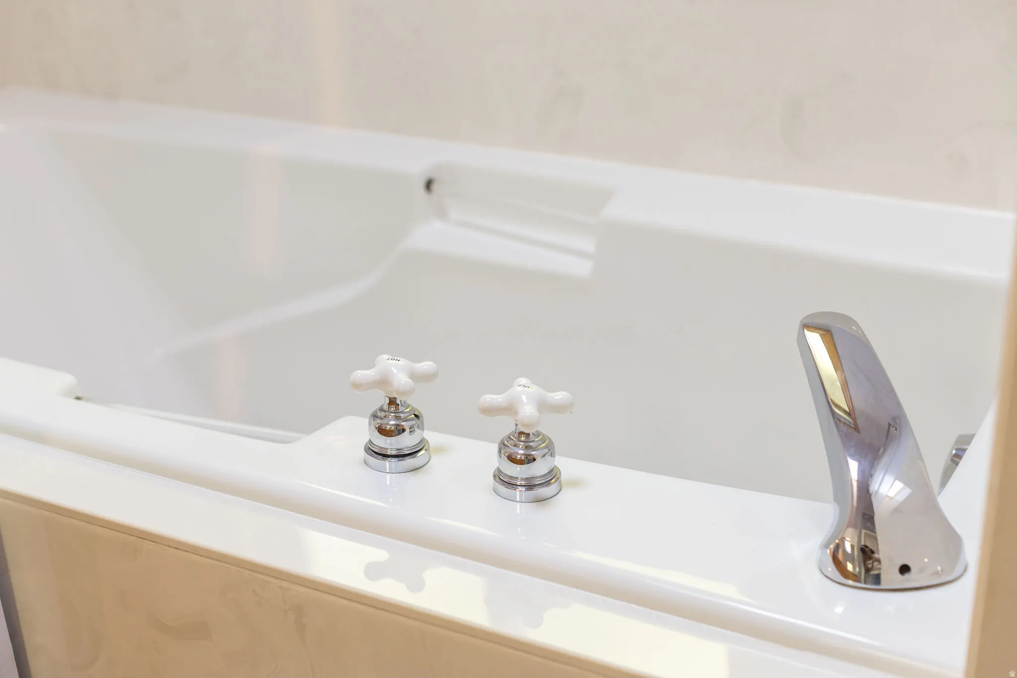 Built-in bathtub with integrated headrest, chrome fixtures, and classic white cross-handle controls