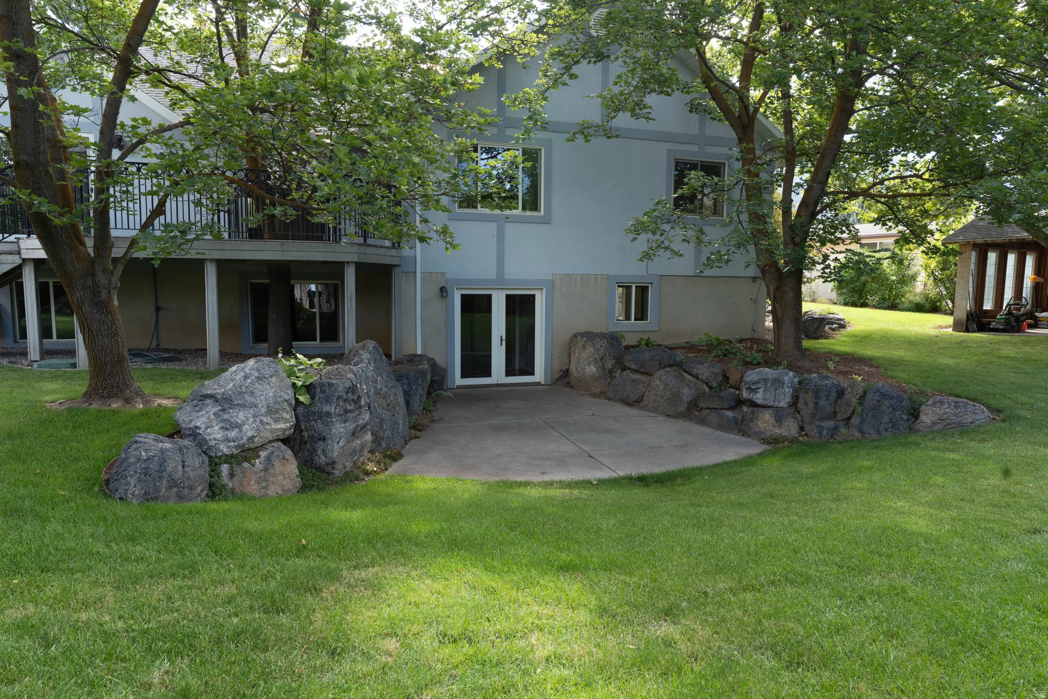 Expansive lawn with mature trees and a concrete patio