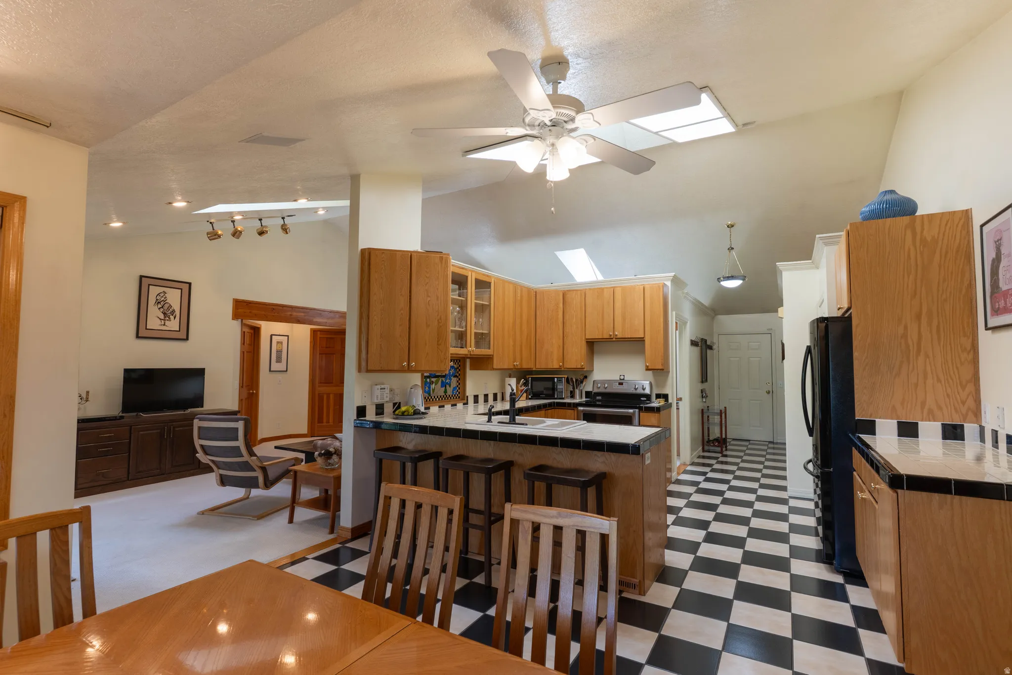 Kitchen featuring wood cabinetry, black and white checkered flooring, and a breakfast bar with tile countertop