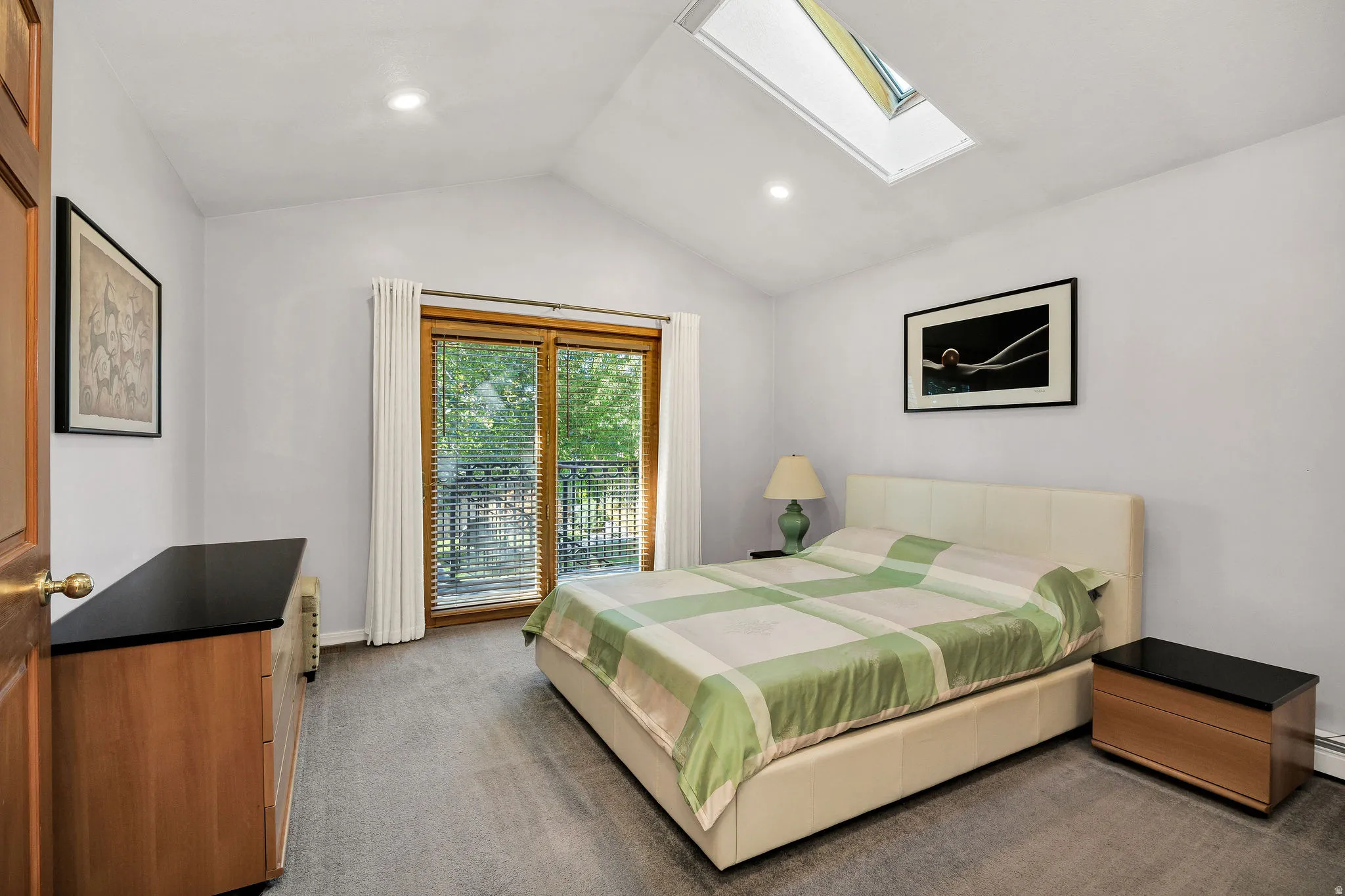 Vaulted ceiling with skylight, recessed lighting, wall-to-wall carpeting, and wood-frame sliding glass doors