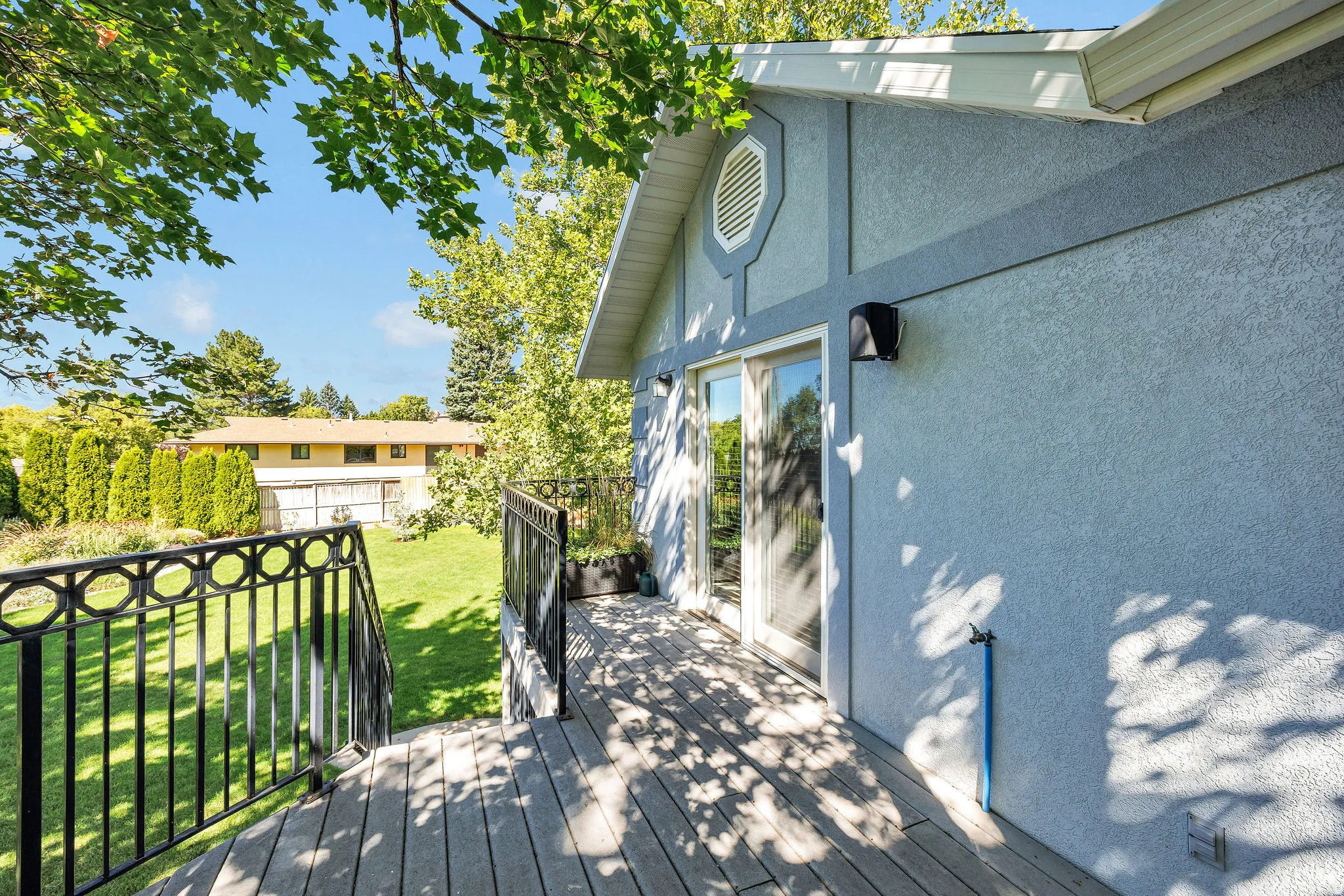 Spacious exterior deck with wood-finish decking, decorative metal railings, and direct access to a grassy yard