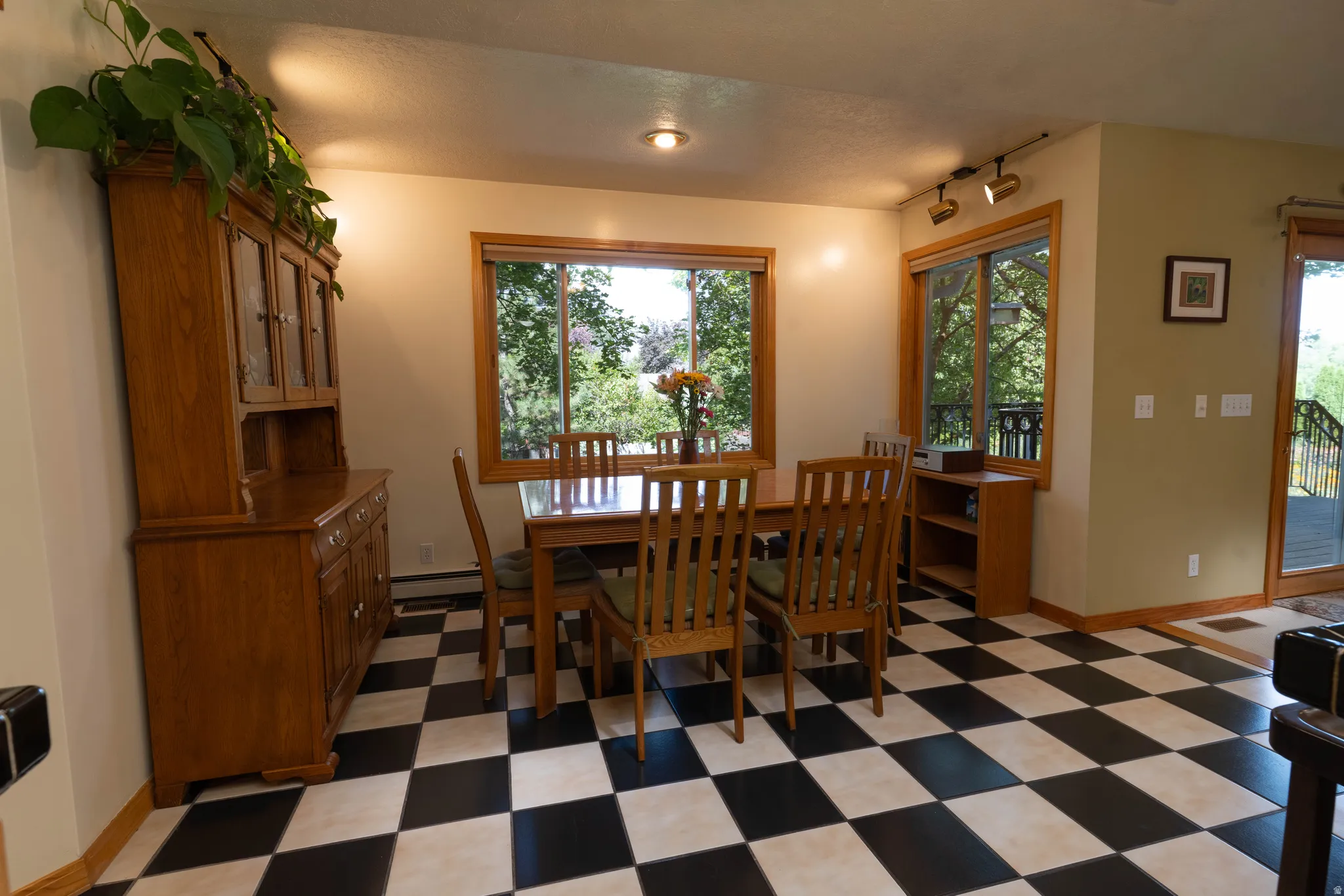 Black and white checkered tile flooring, wood-framed windows, recessed lighting, track lighting, and a sliding glass door with exterior access