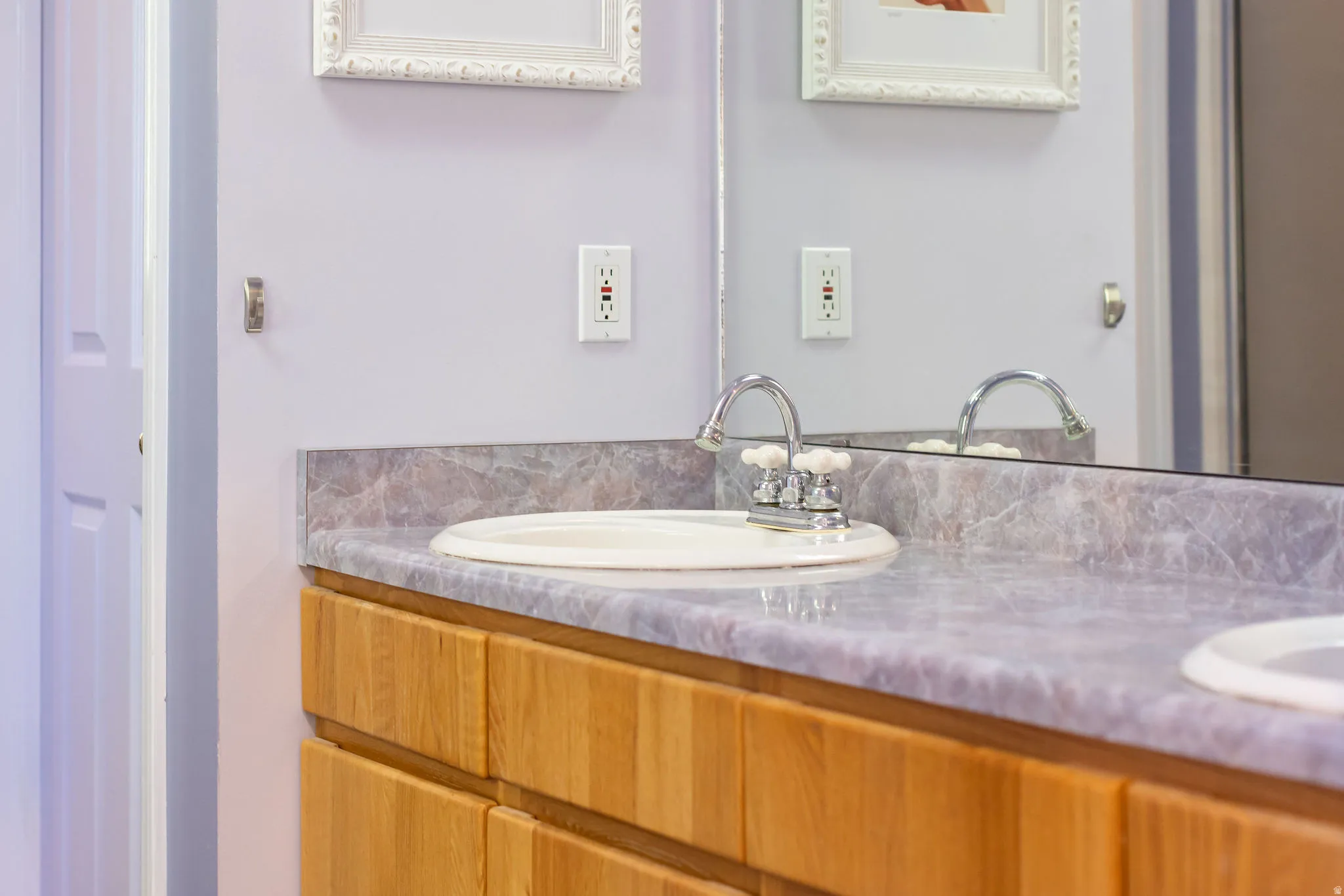 Dual vanity with undermount sinks, wood-finish cabinetry, and a marbled countertop