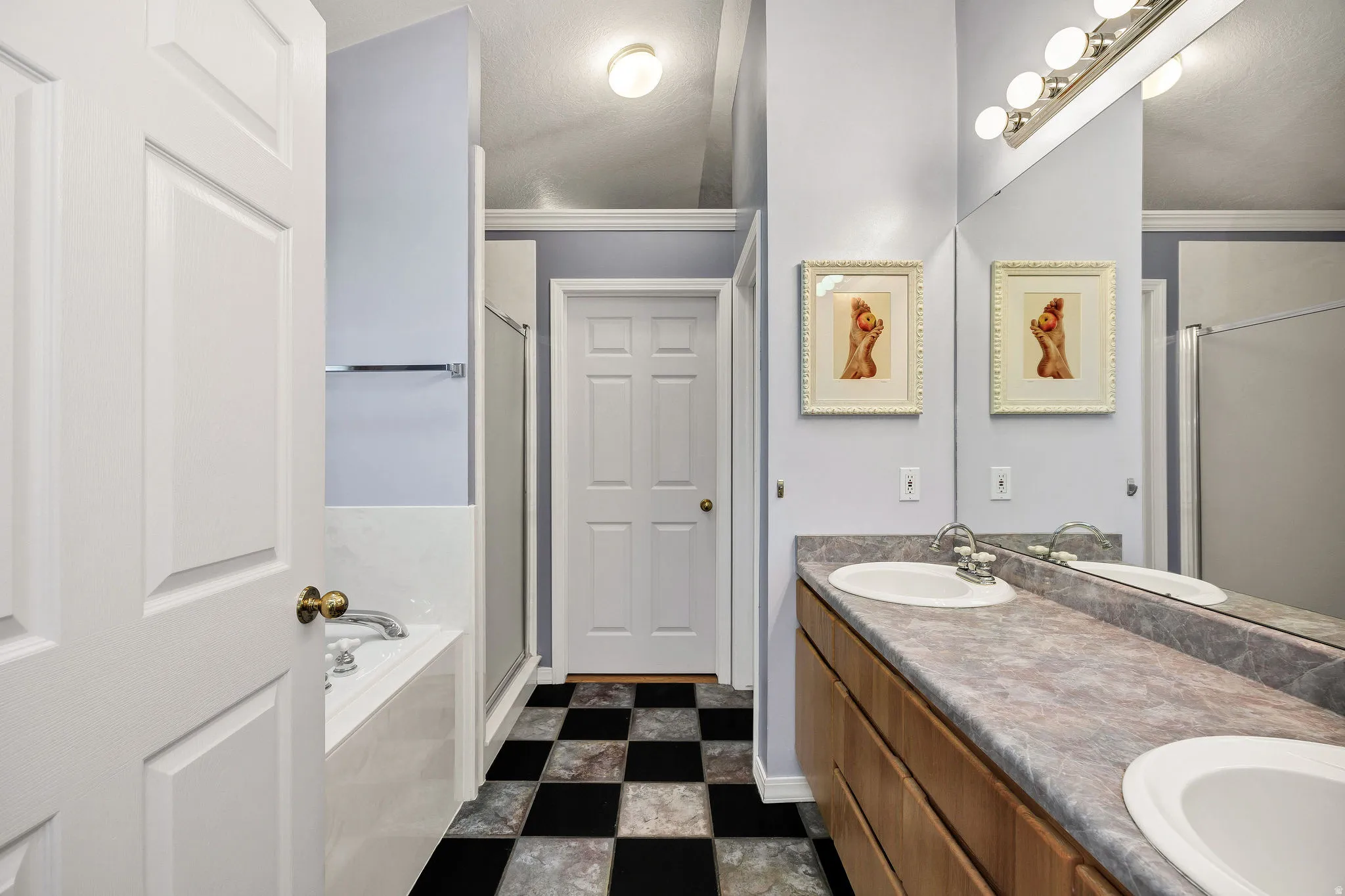Dual vanity with integrated sinks, full-width mirror, wood-finish cabinetry, and overhead bar lighting