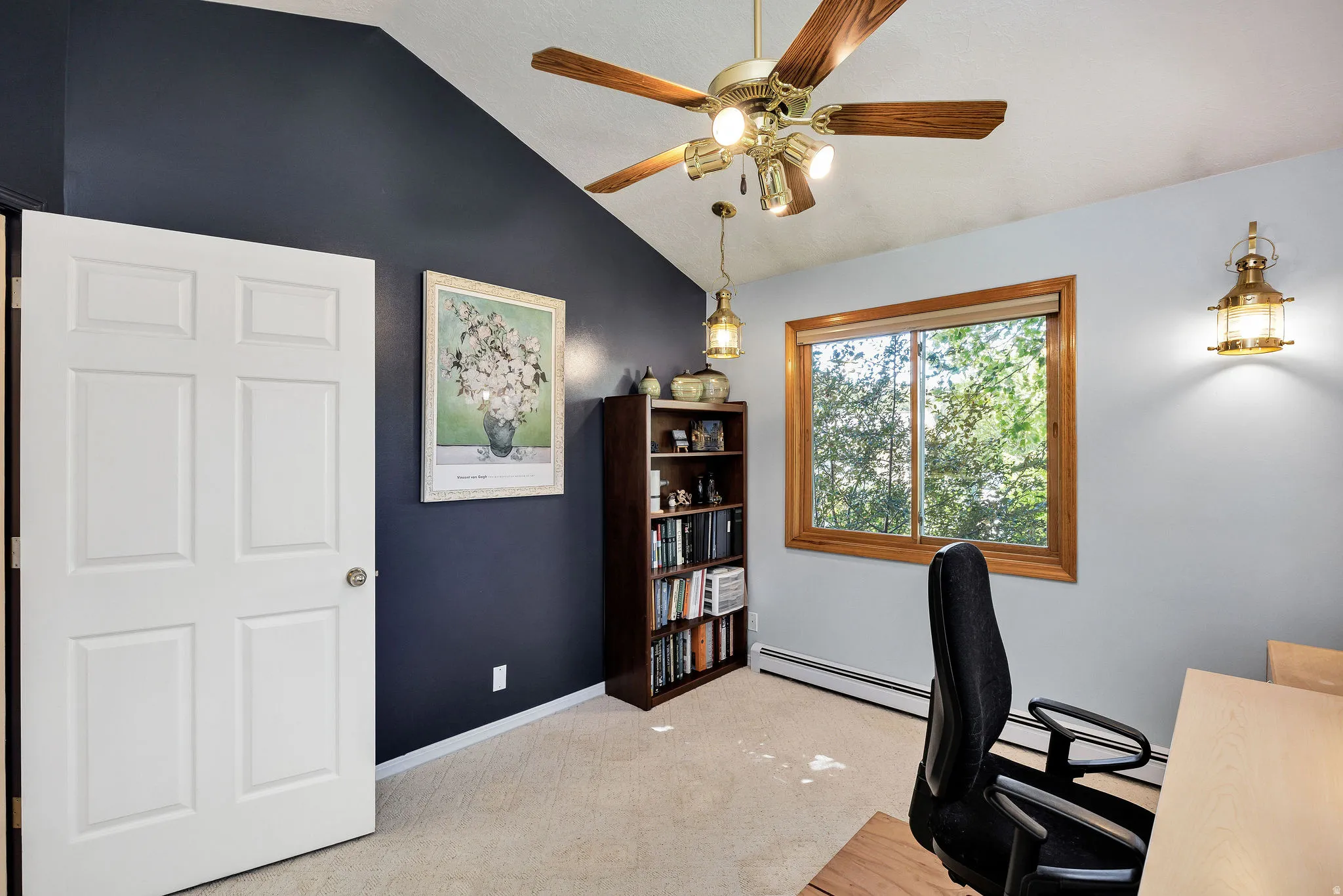 Vaulted ceiling with a brass-finish ceiling fan, wood-frame window, and wall-mounted lantern-style lighting fixtures