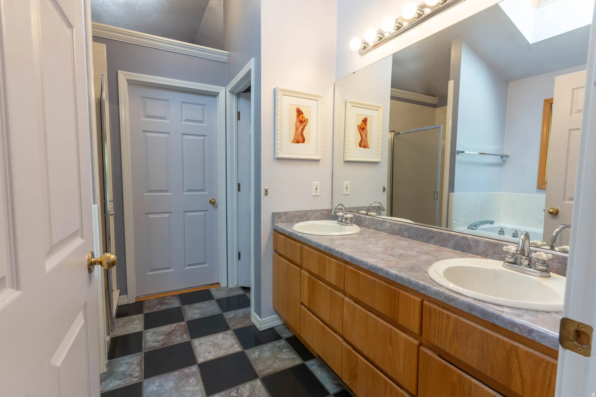 Dual vanity with undermount sinks, wood-finish cabinetry, and a large mirror