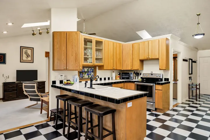 Kitchen with wood cabinetry, stainless steel appliances, breakfast bar, and checkerboard floor tiling