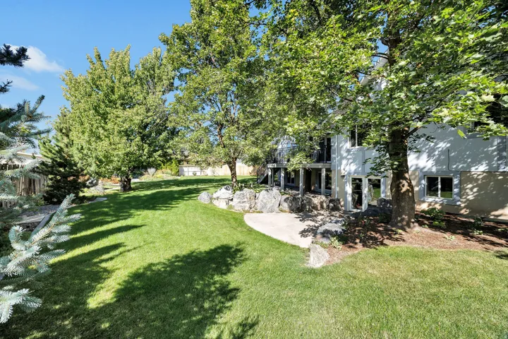 Expansive green lawn with mature trees and a concrete patio