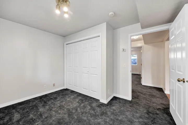 Recessed ceiling light fixture, white bi-fold closet doors, and dark-toned carpet flooring