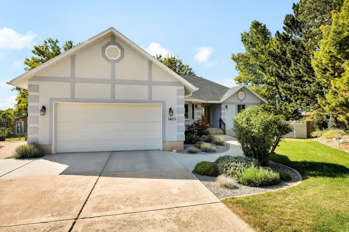 Light-toned exterior with distinct grey trim accents, attached garage with panel door, and concrete driveway