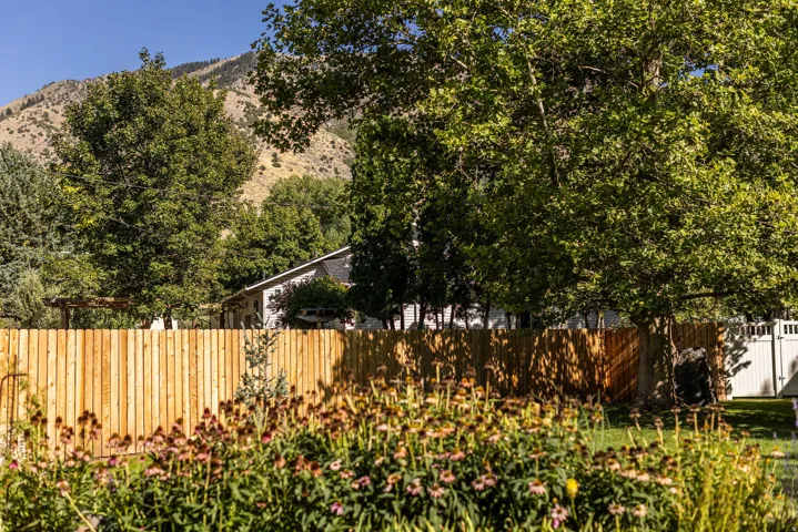 Expansive backyard featuring a new wood privacy fence, mature trees, and perennial plantings