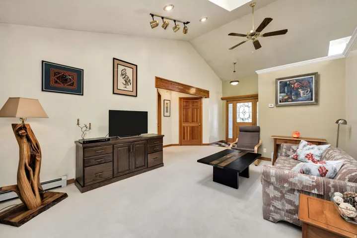 Spacious open-concept living area featuring vaulted ceilings with skylights, ceiling fan, and recessed lighting