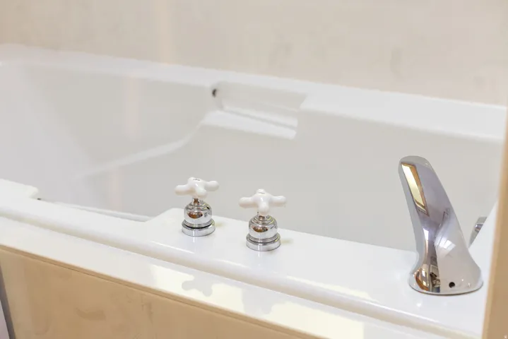 Built-in bathtub with integrated headrest, chrome fixtures, and classic white cross-handle controls