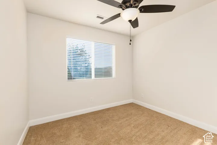 Neutral wall color, window with blinds, ceiling fan with integrated lighting, and carpet flooring