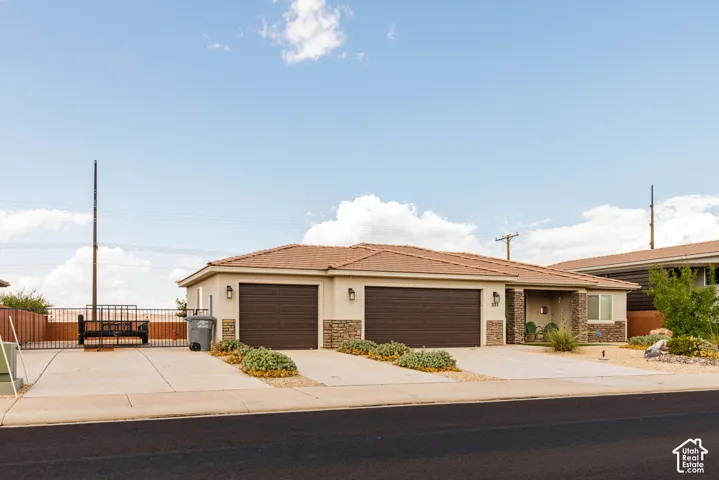 Stucco exterior with stone accents, dual two-car garages, covered entry, and a tiled roof