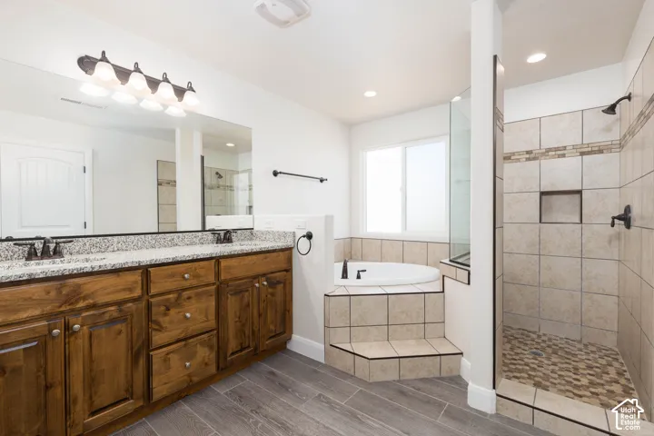 Dual vanity with granite-style countertop, wood-finish cabinetry, and undermount sinks