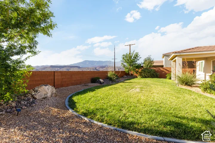 Expansive grass lawn with surrounding gravel landscaping, concrete curbing, and a block privacy wall