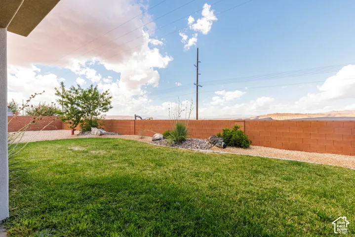 Expansive backyard featuring a manicured lawn, gravel pathways, and a block privacy fence