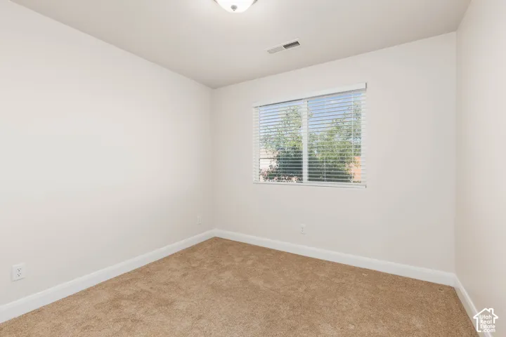 Neutral-toned carpeting, white walls, and a window with horizontal blinds
