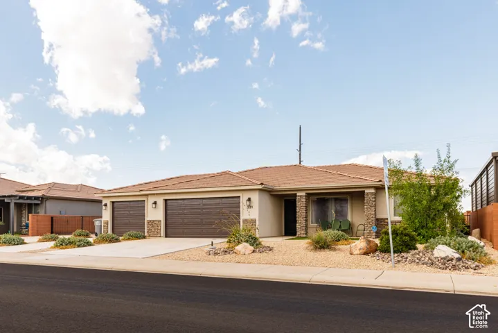 Single-story residence featuring a tile roof, dual garage doors, and a covered porch entry