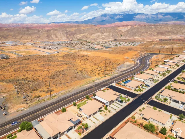 Expansive desert landscape with distant mountains, featuring a residential community with uniform roofing and paved streets