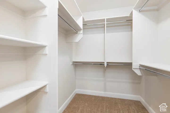 Walk-in closet with integrated shelving, multiple hanging rods, and neutral-toned carpeting