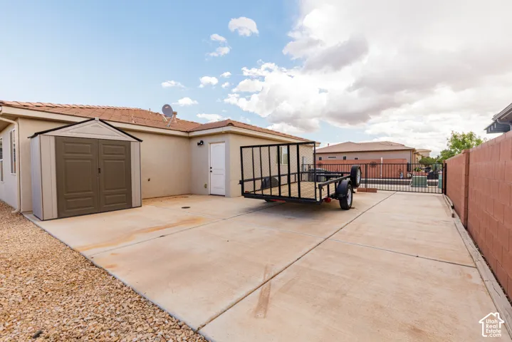 Concrete patio with a storage shed, exterior door, and gravel landscaping