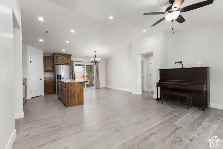Vaulted ceilings with recessed lighting, wood-finish flooring, and a kitchen island with built-in sink